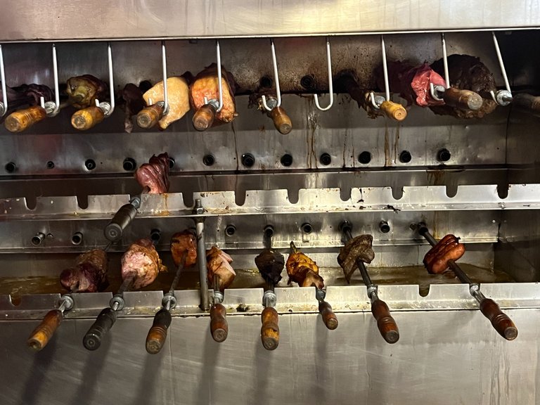 various meats on skewers. they cut off the surface to give you a charred piece on your plate