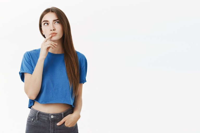 creative-smart-and-thoughtful-attractive-european-woman-in-trendy-blue-cropped-top-making-hmm-gesture-with-finger-on-lower-lip-raising-eyebrow-and-gazing-up-thinking-making-choice-in-mind.jpg