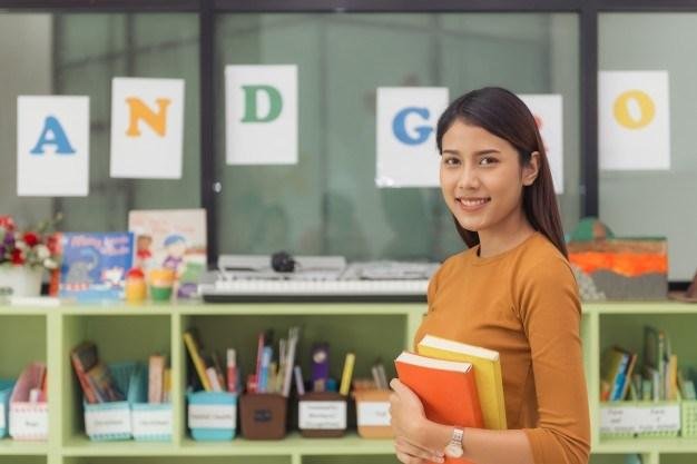 pretty-asian-teacher-smiling-at-camera-at-back-of-classroom-at-the-elementary-school-vintage-effect-style-pictures_1253-1133.jpg