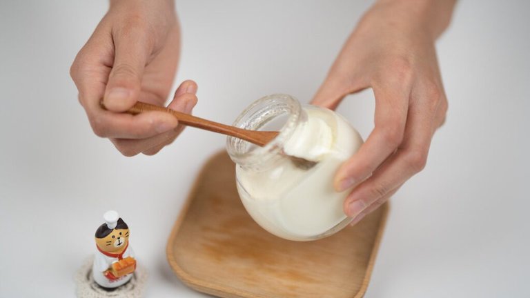 Crop man taking natural yogurt with spoon from jar
