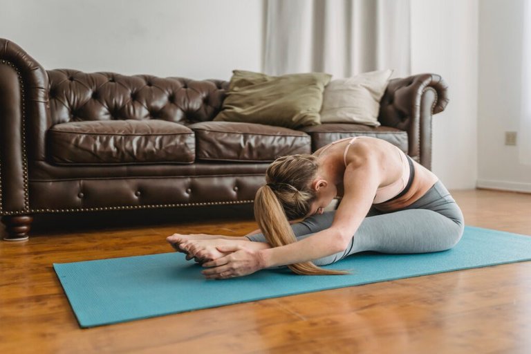 Barefooted woman stretching spine while doing yoga pose
