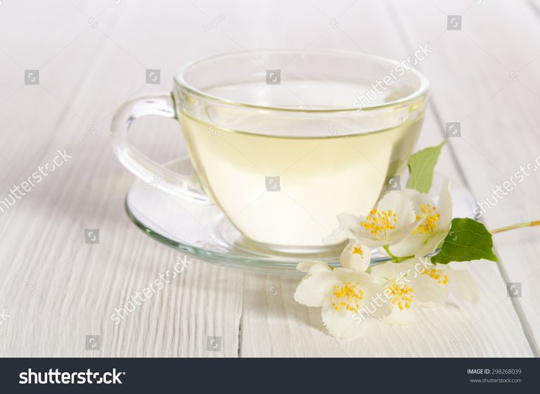 Glass cup of tea with jasmine on the white wooden background