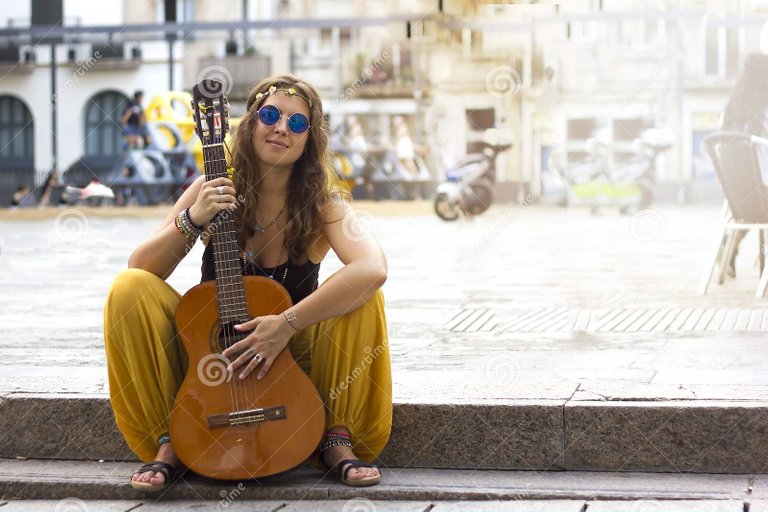 young_curly_girl_rounded_blue_retro_hippie_sunglasses_sitting_outdoors_square_guitar_street_looking_camera_190018228.jpg