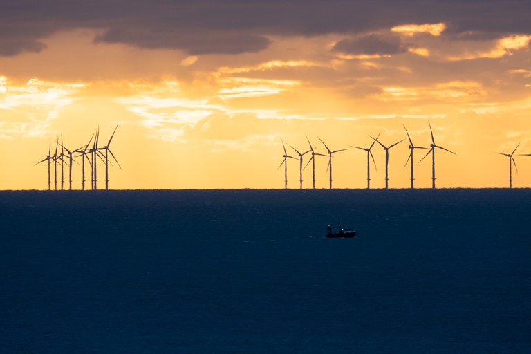 Shot of the Rampion Wind Farm at sunset with a small boat in the foreground