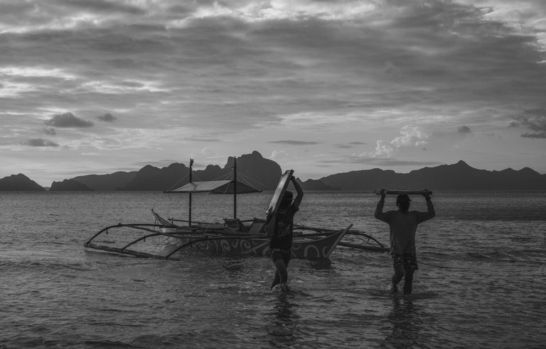 two_men_unloading_a_boat_on_the_beach_1.jpg