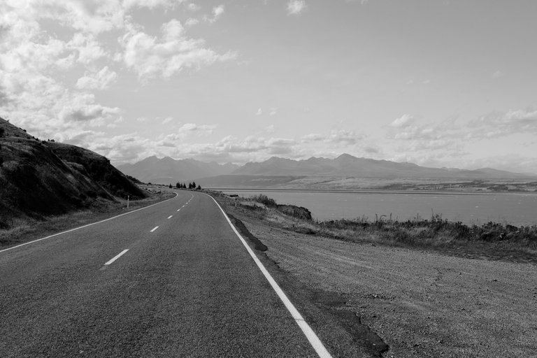 empty_road_with_a_blue_lake_and_mountains_in_the_background_4.jpg
