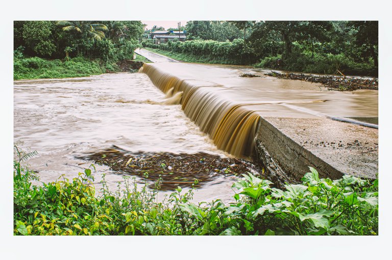 Fotografía de larga exposición diurna de una pequeña crecida del Río Mayarí pasando por encima del puente de Barrio. 