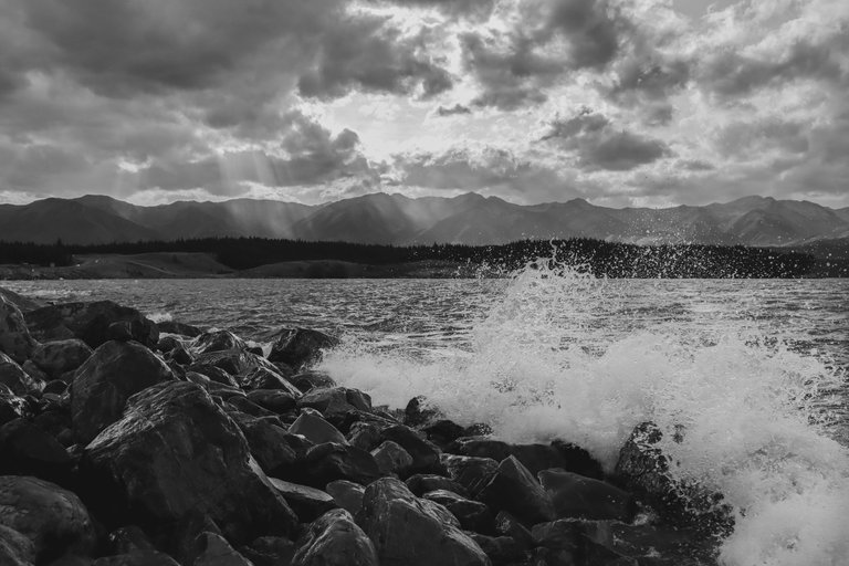 water_crashing_against_rocks_with_the_sunset_over_the_mountains_2.jpg