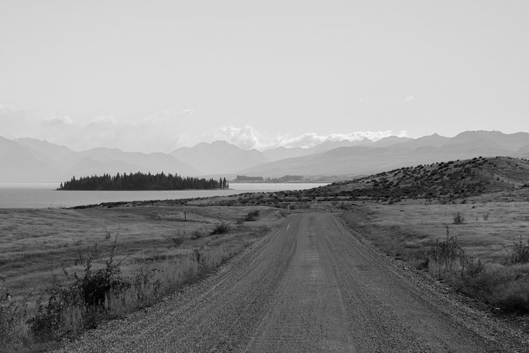 empty_road_with_a_blue_lake_and_mountains_in_the_background.jpg