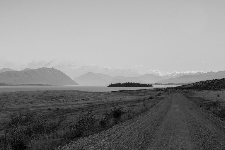empty_road_with_a_blue_lake_and_mountains_in_the_background_2.jpg