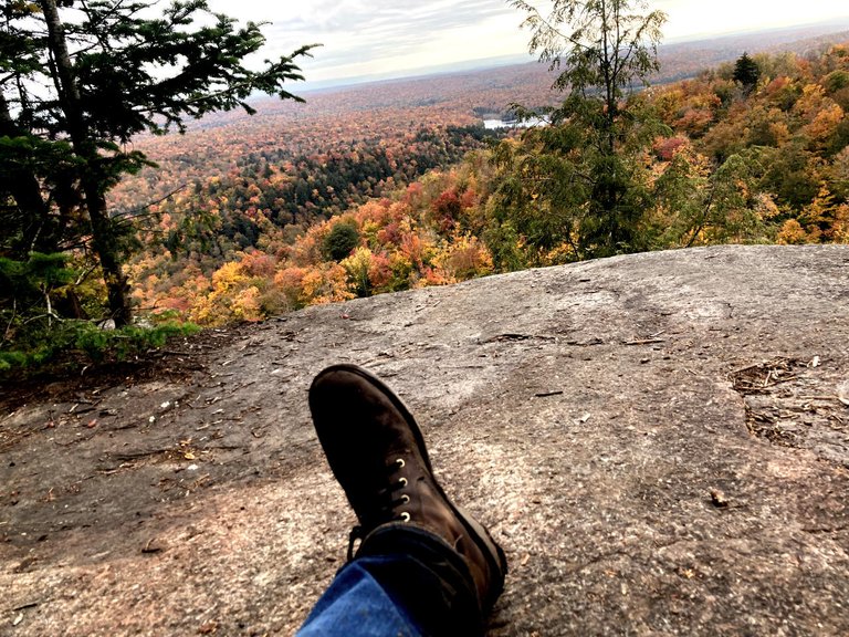 The view at the top of the hill, with a person's muddy boot and jeans in the foreground