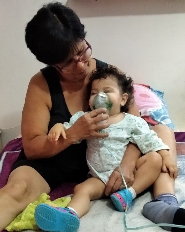 La abuelita cuidando de Sofía y enseñando el como convencerla para que se haga la terapia respiratoria