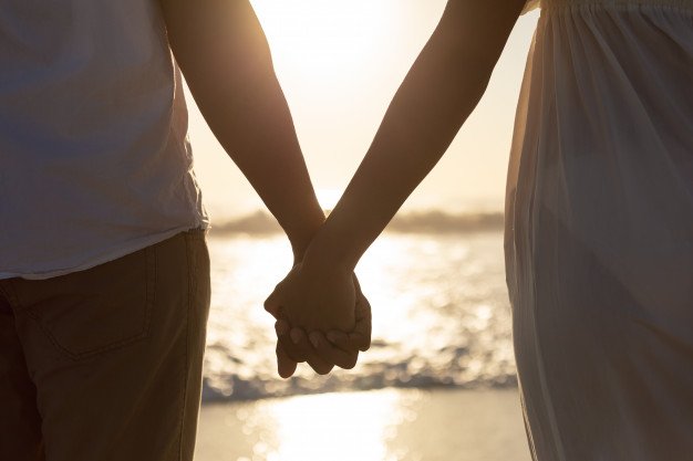 couple-standing-together-hand-hand-beach_107420-10016.jpg