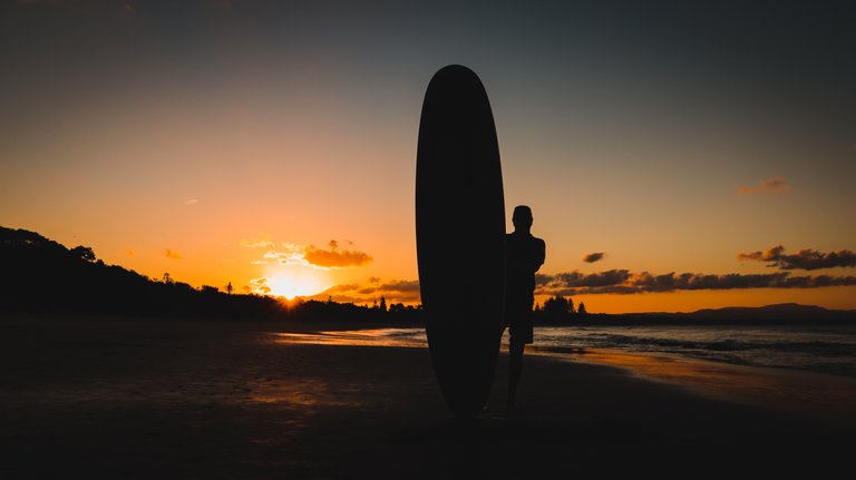 silhouette_of_a_man_holding_up_a_surf_board.jpg
