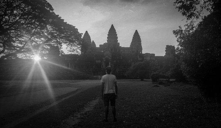 man_facing_backwards_looking_at_angkor_wat_at_sunset.jpg