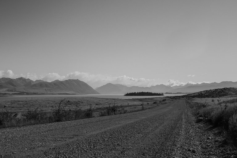 empty_road_with_a_blue_lake_and_mountains_in_the_background_3.jpg