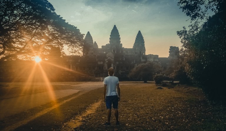 man_facing_backwards_looking_at_angkor_wat_at_sunset.jpg