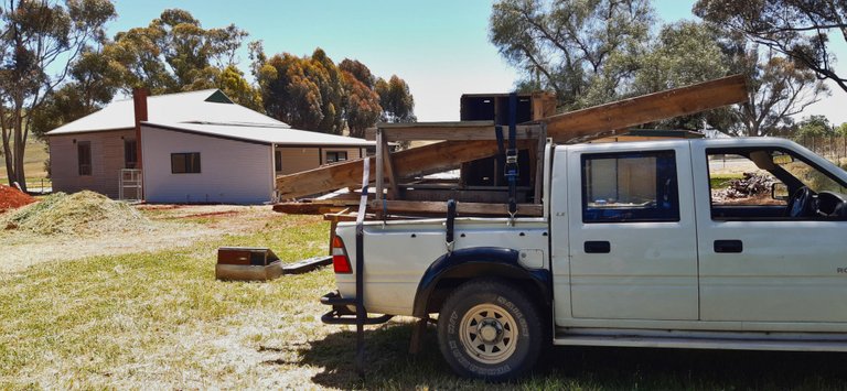 Ute with pile of timber and firewood, Washpool Hall in background