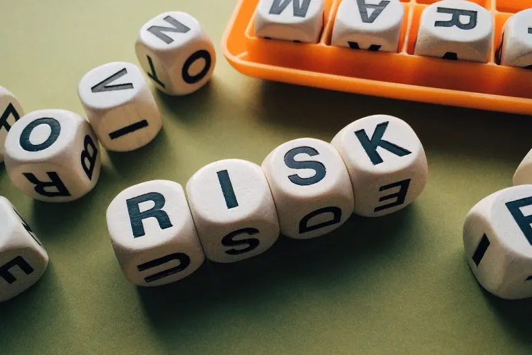 Four dice with letters on their faces spelling the word risk