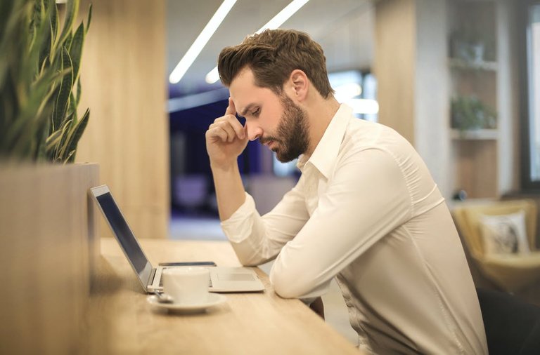 Free Man With Hand on Temple Looking at Laptop Stock Photo