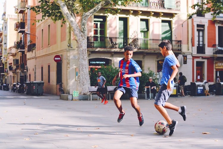 Picture of two boys playing soccer in the street