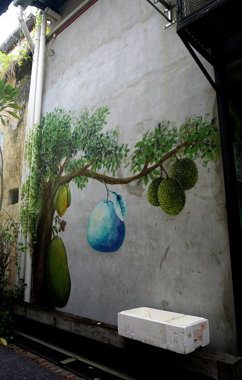 Hmmm, street art - a durian tree with some magical blue fruit? Looks like a pomelo to me. Ipoh is well-known for their pomelos... why blue, I wonder... Edit: Silly me - didn’t notice, it has different Malaysian fruits on the one tree! Huge jackfruit on the trunk (that’s how jackfruits grow...), a bunch of much smaller reddish rambutans above (rambutans = the very sweet hairy fruit), papayas above that, in a cluster of three, durians to the right, with thorns, also a bunch of three!