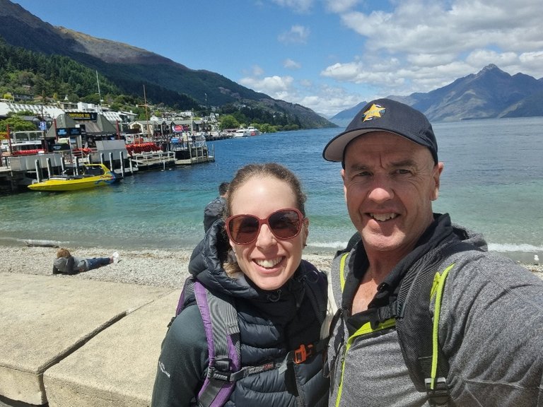 Queenstown is on the South Island of New Zealand, towards the bottom left (or South West) corner of this tree-covered island. The town itself is arranged around the lake you see in this photo behind us. It’s called Lake Wakatipu and to say it’s *gorgeous* would be a good start.