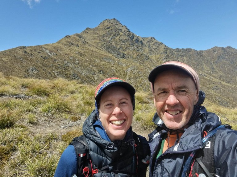 And another photo, this time of us, perhaps an hour further up the hill with the top of Ben Lomond in the background and finally in our sights. From this point (which I think is called ”The Saddle”, where the maintained track gives way to a *goat track*) it was about another hour of steep, difficult, windy climbing. It was difficult and I had to rest for a minute or two every 10 minutes or so, but it was so worth it. Totally beautiful, totally amazing. You can read more about Ben Lomond via Brad’s post that you’ll find here.