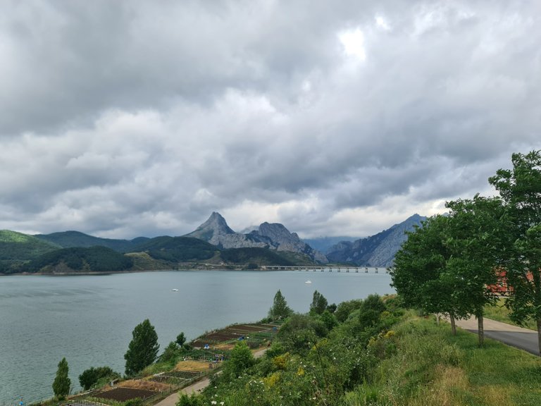 Small orchards on the banks of the Riaño reservoir and the Riaño bridge and the Gilbo peak in the background.