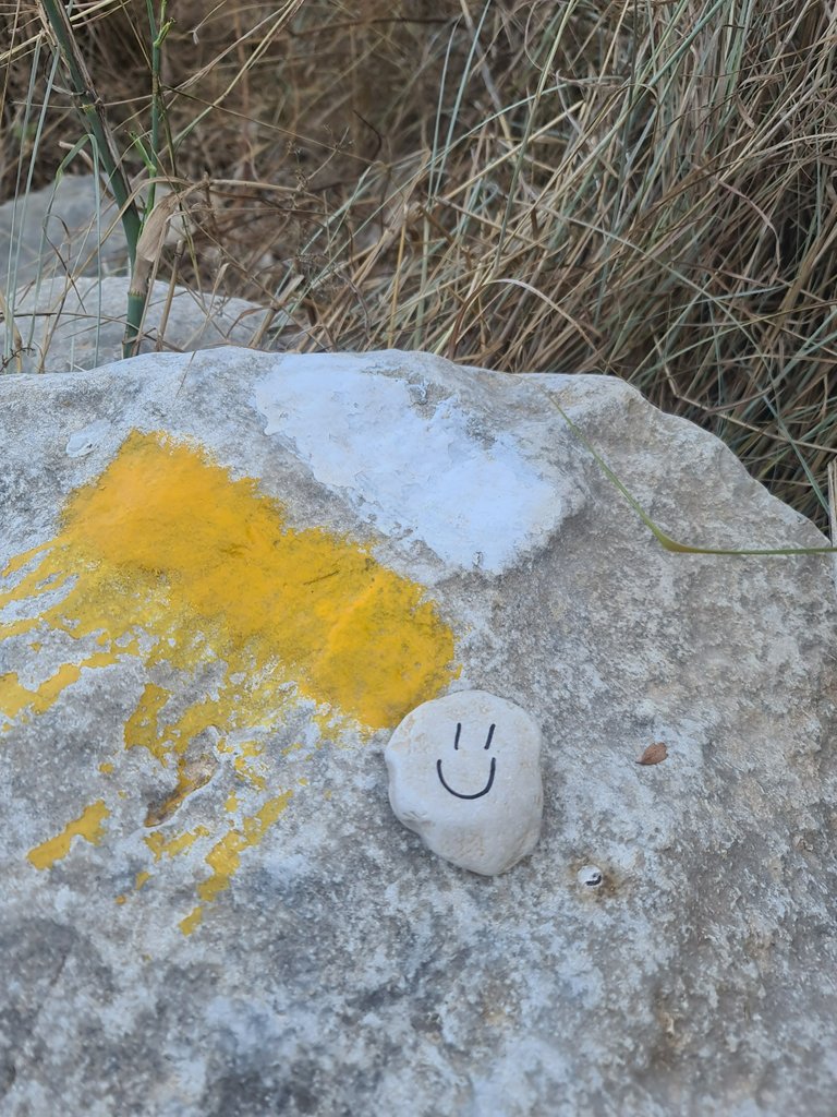 Signage painted on the rock in yellow and white colors informing you that you’re on the route (and a happy face on a small stone).