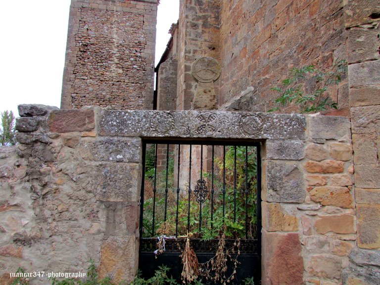 Gate of the small church cemetery, with Templar symbols and funerary stele