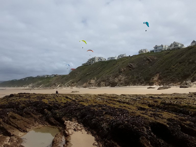Paragliders above the rock pools and mansions of Wilderness beach