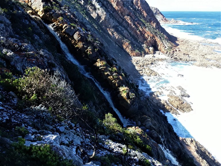 An amazing flow of fresh rain water pouring down the cliff side to the ocean below