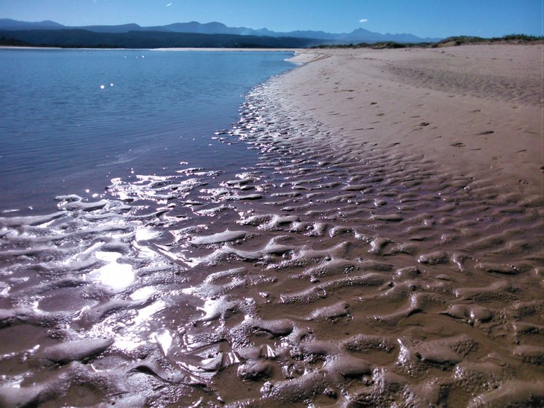 Epic sun reflections on the rippled lagoon bed with the Tsitsikamma mountain range in the background