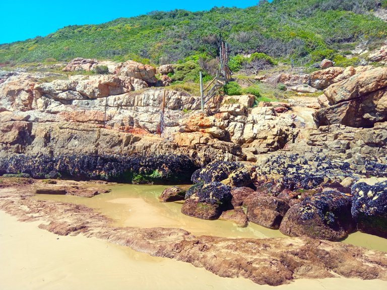 Where the beach meets the peninsula, the sea washes up from the left.