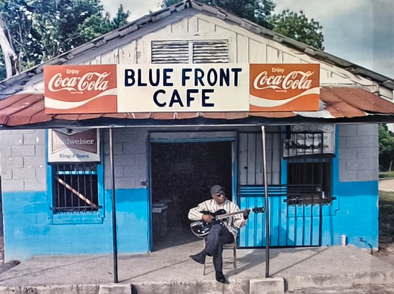 A bluesman, playing in front of a small shop