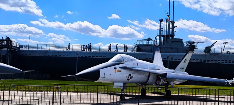 An airplane in front of the USS Drum