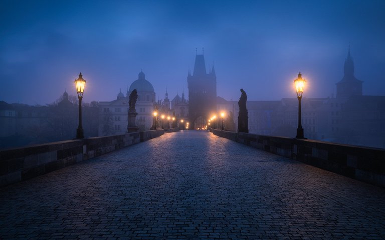 Blue hour in Prague with fog shrouding the famous Charles Bridge