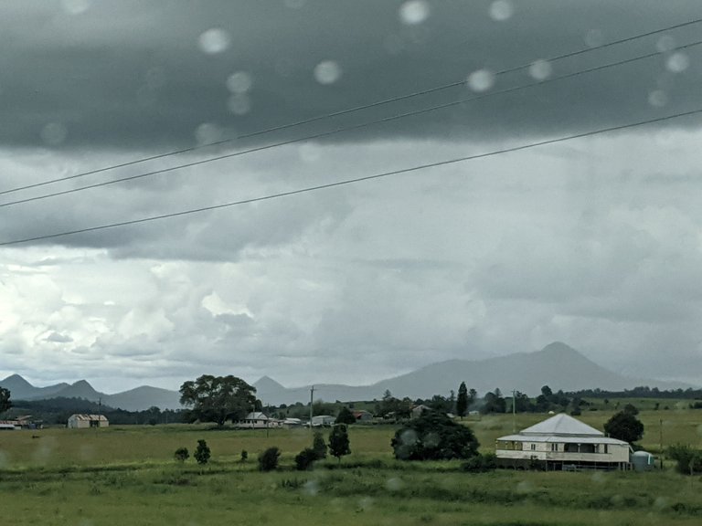 Some of the Scenic Rim mountains in the background with a typical country Queensland house in the foreground. These houses are built with large verandas all around the outside to give shade from the predictably hot summer sun and allow breeze in through the house.