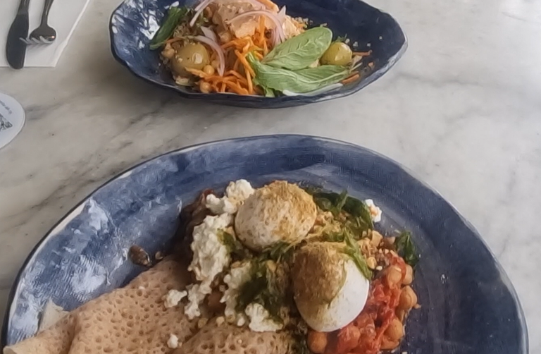 I had the Healthy Breakfast closest. $19.90 Aud two free range poached eggs, roasted eggplant & tomato marinated feta, chickpeas, za’atar, fried basil, dukkah, injera bread. I have never heard of half this stuff but it was good. @consciouscat had the Smoked Trout Salad at the top of picture.