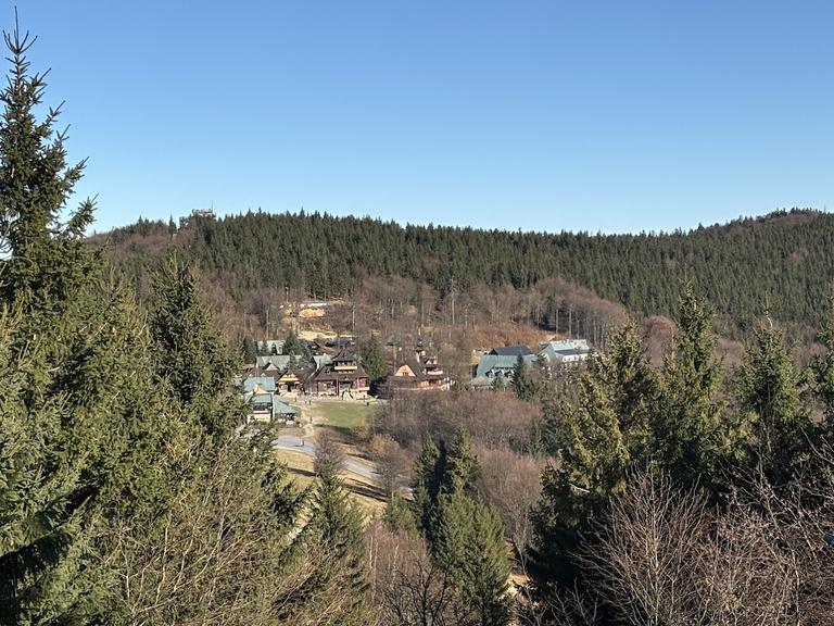 Widok na Pustevny ze szlaku w kierunku Radegasta. W oddali, po lewej - ”Stezka Valaška”.