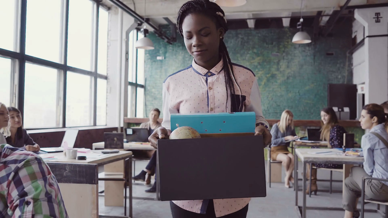 videoblocks-young-african-woman-getting-fired-from-work-female-walks-through-the-office-carrying-box-with-personal-belongings_hr8dcwpgz_thumbnail-full11.png