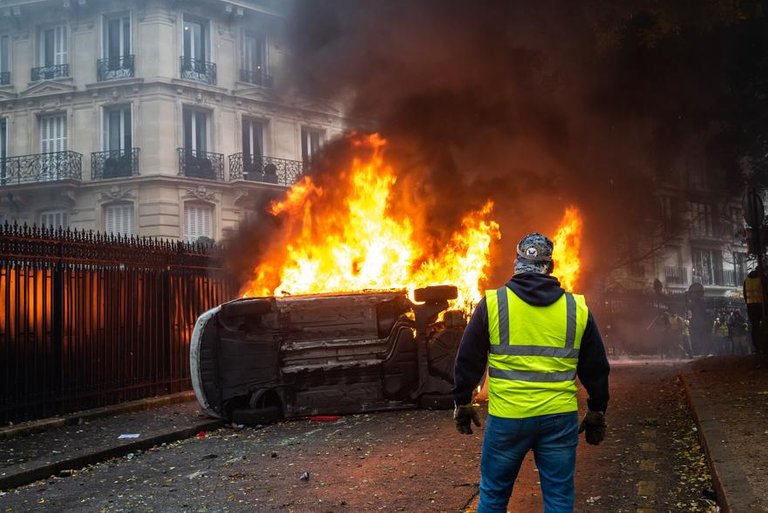 7795779632_un-gilet-jaune-devant-un-voiture-en-train-de-bruler-avenue-foch-non-loin-de-l-arc-de-triomphe-a-paris.jpg