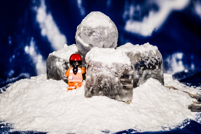 A lego figurine posed with ice cubes and flour to give the appearance of climbing a mountain