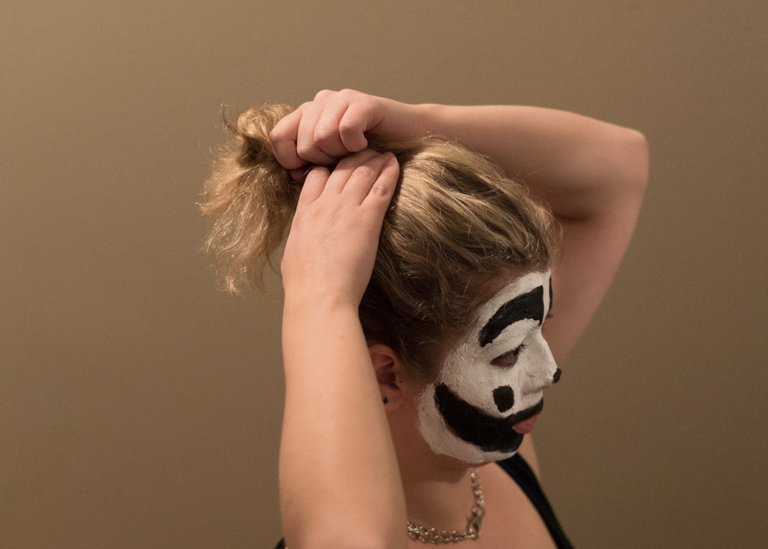 A Juggalette putting their hair up in a ponytail