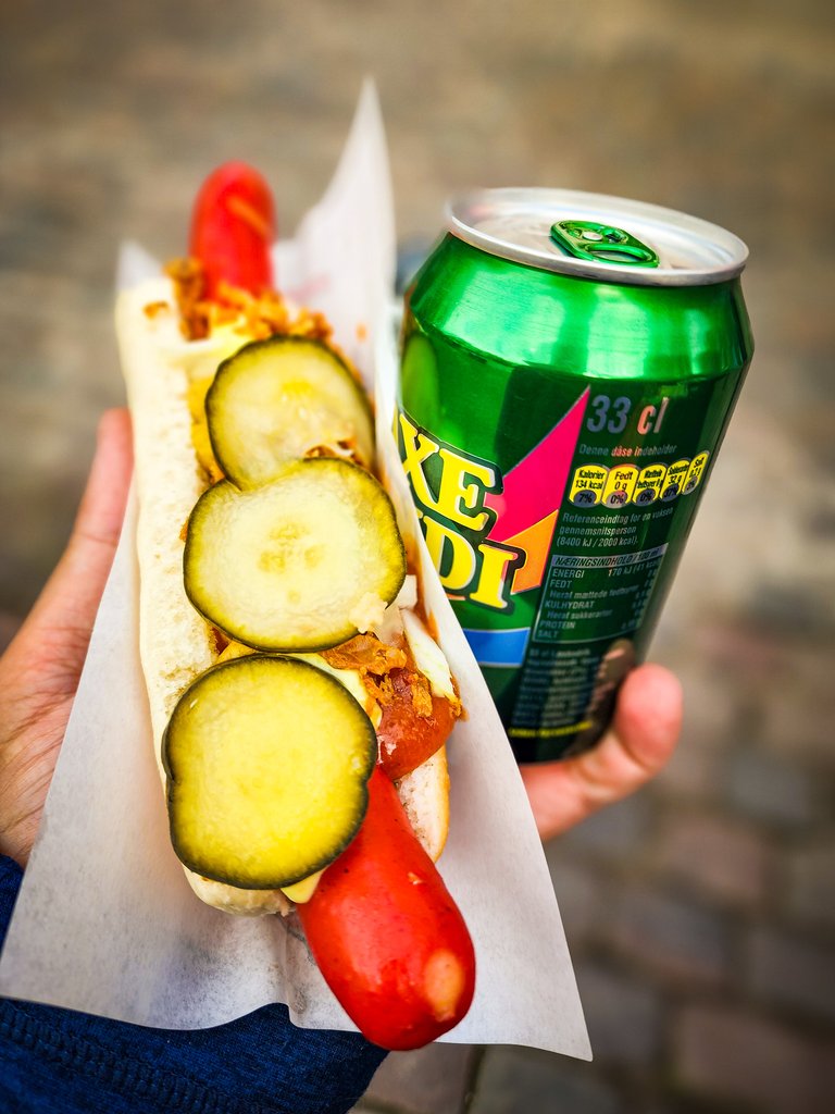 Danish hot dog with sliced cucumber, pickles, and mustard