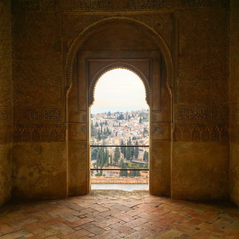 A typical Moorish arch overlooking overlooking the terracotta roofs of Granada far below.