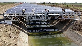 Indian workers give finishing touches to installed solar panels covering the Narmada canal at Chandrasan village, outside Ahmadabad, India, April 2012. 