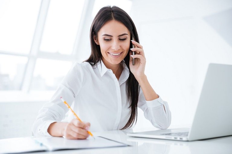 graphicstock-business-woman-talking-at-phone-and-writing-something-in-documents-by-the-table-with-laptop_SIdYvXu3g.jpg