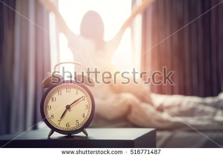 stock-photo-closeup-alarm-clock-having-a-good-day-with-background-happy-woman-stretching-in-bed-after-waking-up-516771487.jpg